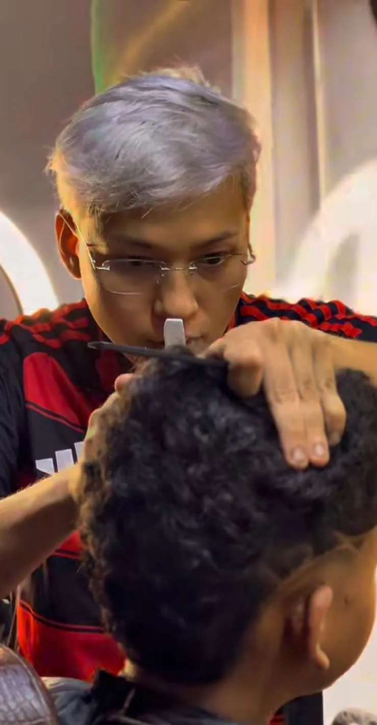 Barbeiro da Barbearia Nakamura finalizando um corte com máquina