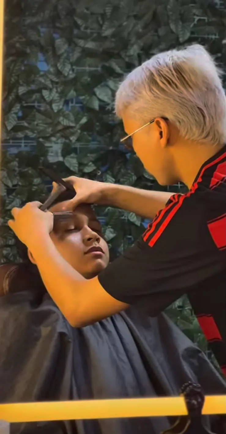 Barbeiro ajustando o corte com o cliente já protegido pela capa